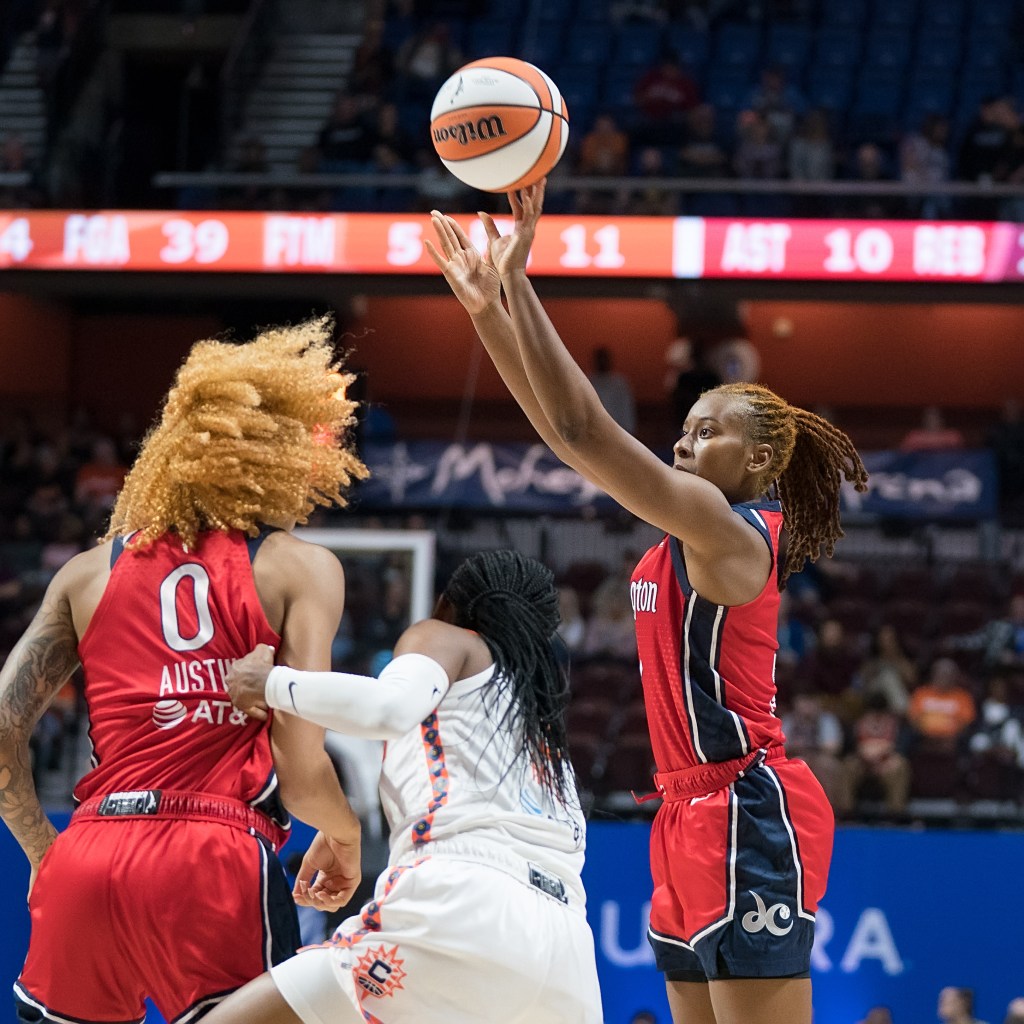 Washington Mystics guard Ariel Atkins shoots a jump shot as a Connecticut Sun defender is late getting around Mystics center/forward Shakira Austin to contest it.