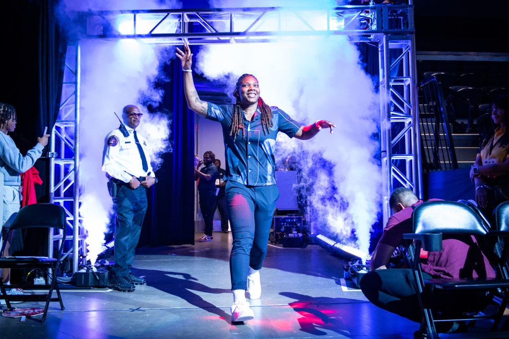 Washington Mystics forward Myisha Hines-Allen waves to the crowd with her right hand as smoke billows out behind her during player introductions.