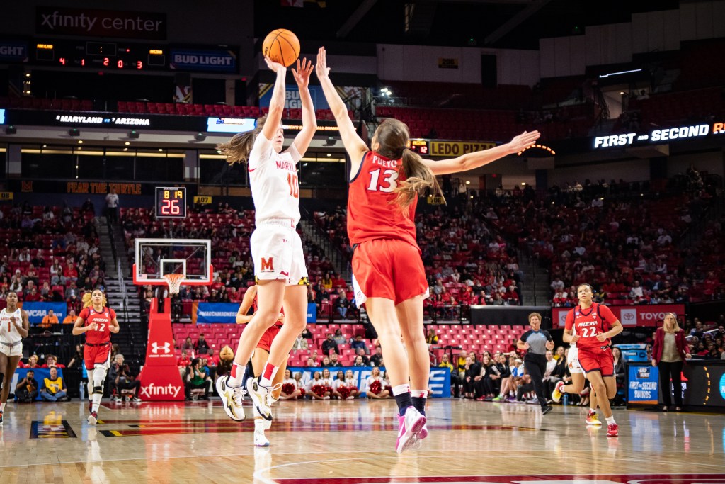 Maryland guard Abby Meyers shoots a jump shot from near the elbow as Arizona guard Helena Pueyo closely contests it with her left hand.