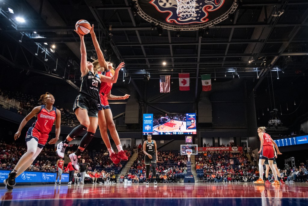 Washington Mystics center/forward Shakira Austin blocks a layup attempt from behind using her right hand.