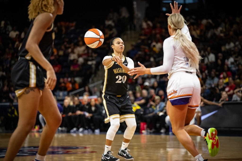 Washington Mystics guard Kristi Toliver passes the ball ahead of her to her right while looking straight ahead.