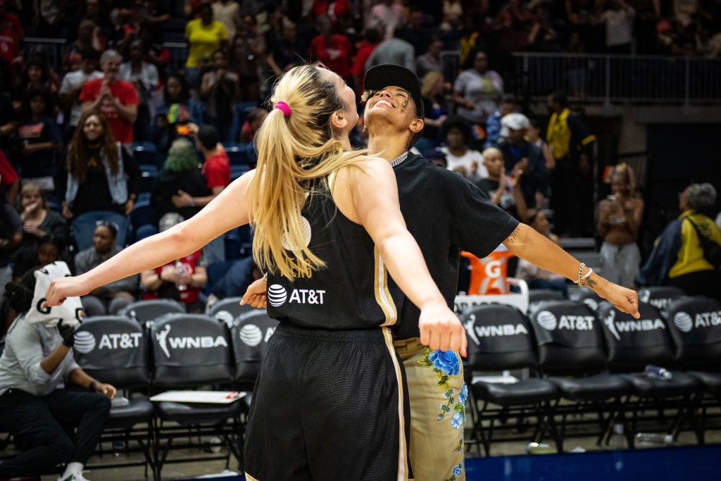 Washington Mystics guards Li Meng and Natasha Cloud bump chests, their arms outstretched behind them.