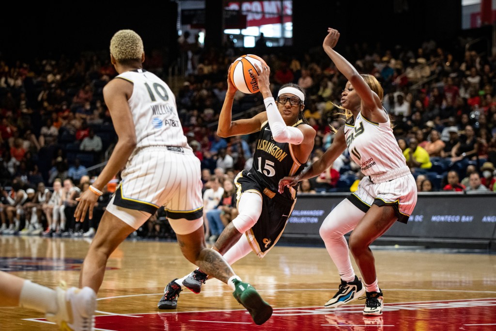 Washington Mystics guard Brittney Sykes gathers the ball with two hands near her head as she drives into the lane against Chicago Sky guard Dana Evans.