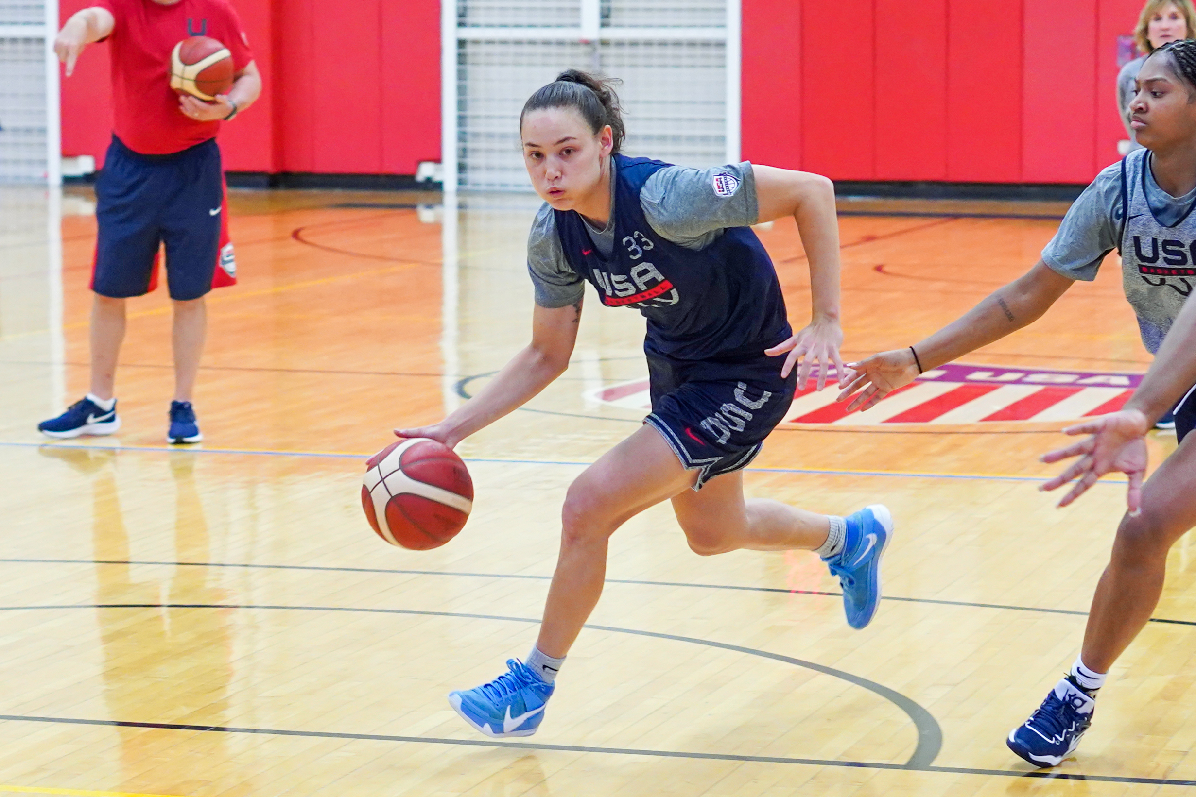 Abbey Hsu dribbles the ball across the free-throw line with her right hand as a defender chases on her left side.