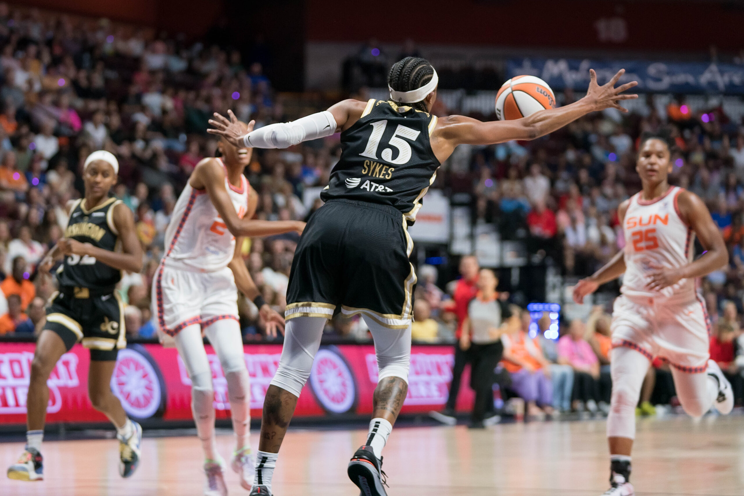 Washington Mystics guard Brittney Sykes extends her right arm to steal a lateral pass from a Connecticut Sun player.