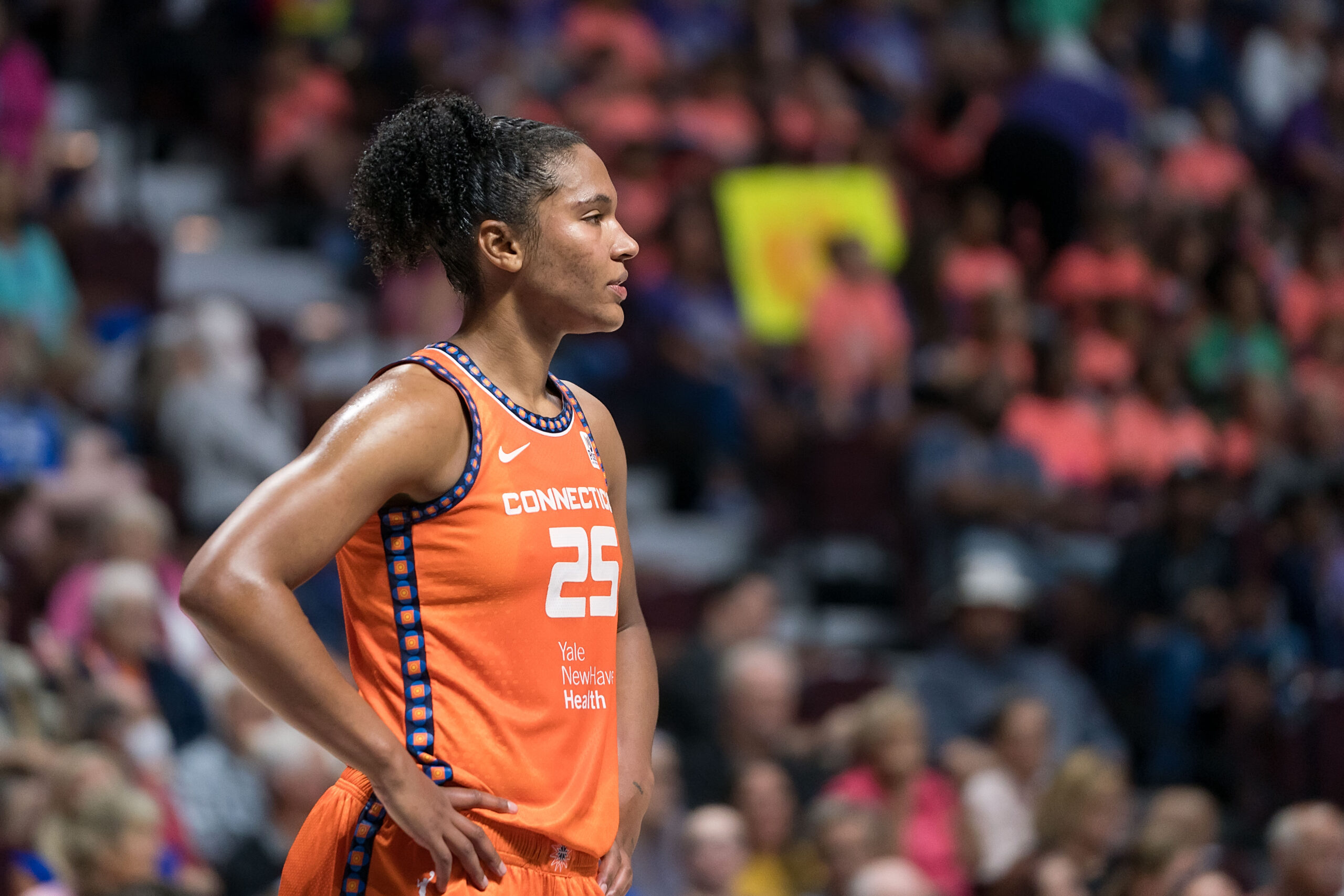 Connecticut Sun forward Alyssa Thomas is shown in profile, standing alone with her hands on her hips and gazing out in front of her.