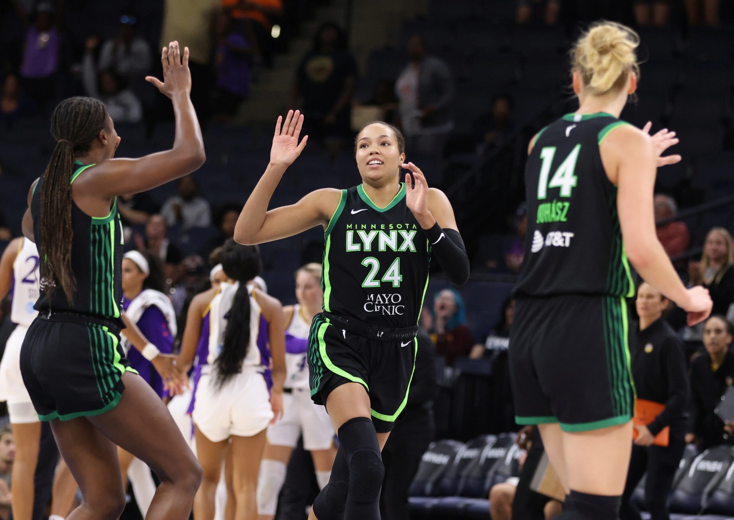 Napheesa Collier has her hands raised to receive high fives from fellow Lynx teammates.