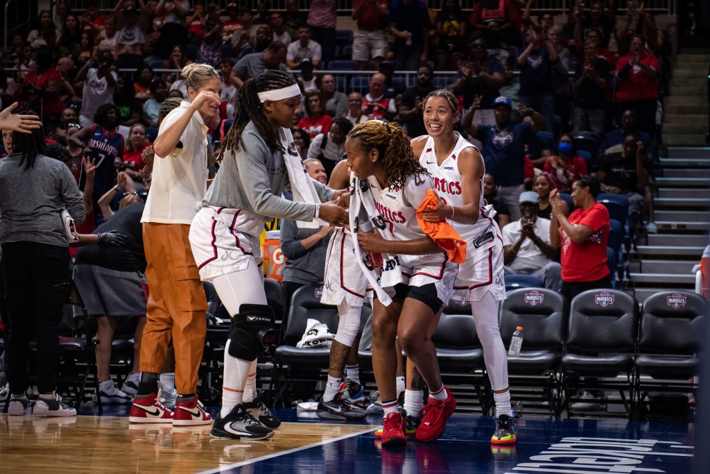Washington Mystics forward Myisha Hines-Allen and guard Natasha Cloud push guard Ariel Atkins toward the baseline to acknowledge the crowd after Atkins set the franchise record for career 3-pointers.