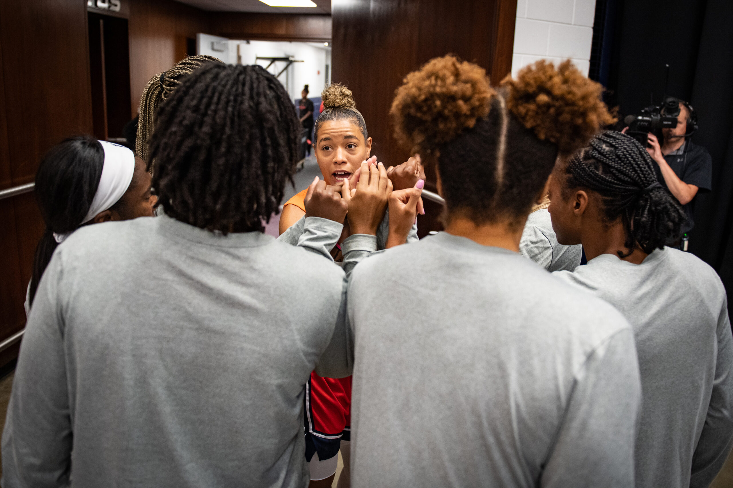 Washington Mystics players put their hands together in a huddle. Point guard Natasha Cloud addresses the group.