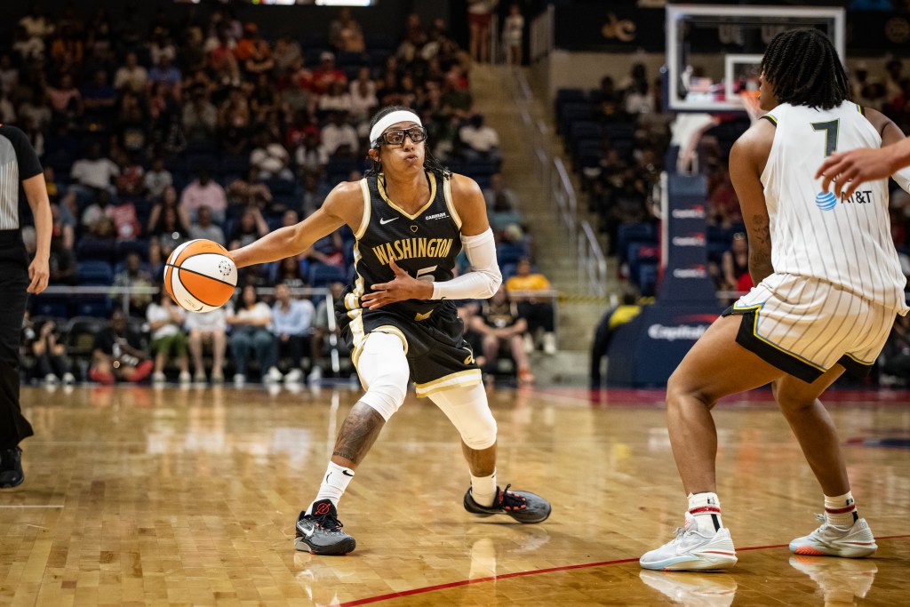 Washington Mystics guard Brittney Sykes controls the ball with her right hand as she scans the court for passing options.