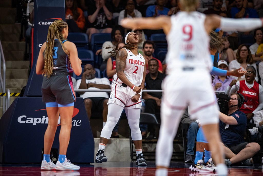 Washington Mystics forward Myisha Hines-Allen flexes her arms downward, lifts her head skyward, and shouts in celebration.