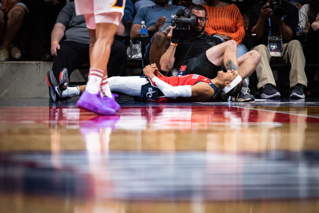 Washington Mystics guard Brittney Sykes lies on her back on the baseline, yelling and clenching her fists in celebration.