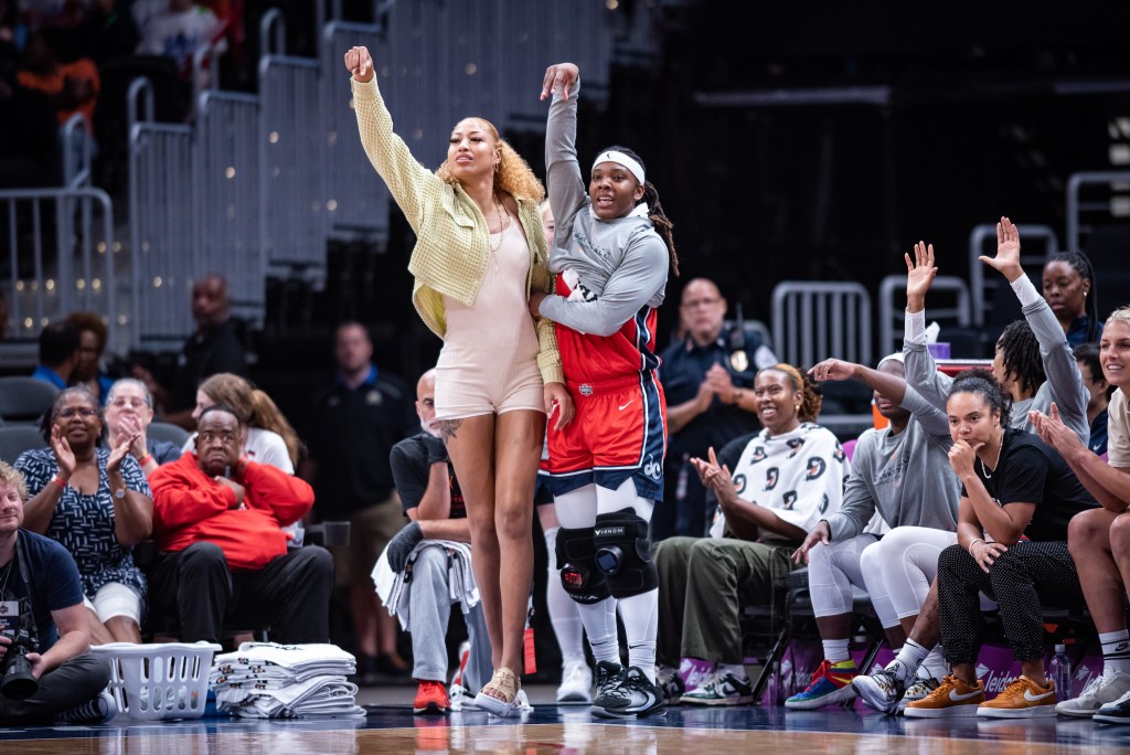 Washington Mystics center/forward Shakira Austin and forward Myisha Hines-Allen celebrate a play by holding their right arms in the air with their fingers tilted down.