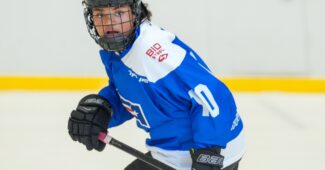 Chloe Brinson is pictured in a blue and white hockey jersey, skating on the ice while participating in the BioSteel Player Development Girls 15 camp.