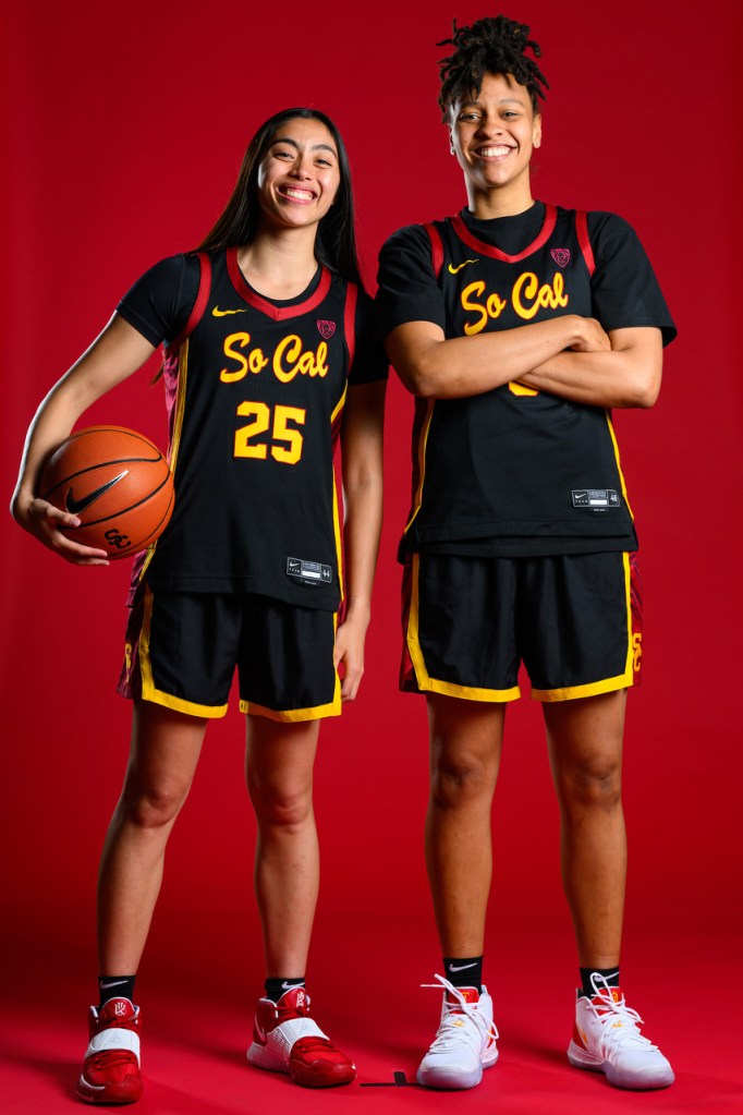 Kayla Padilla and McKenzie Forbes smile for a photo. They're wearing black jerseys that read "So Cal," and Padilla holds a ball against her right hip.