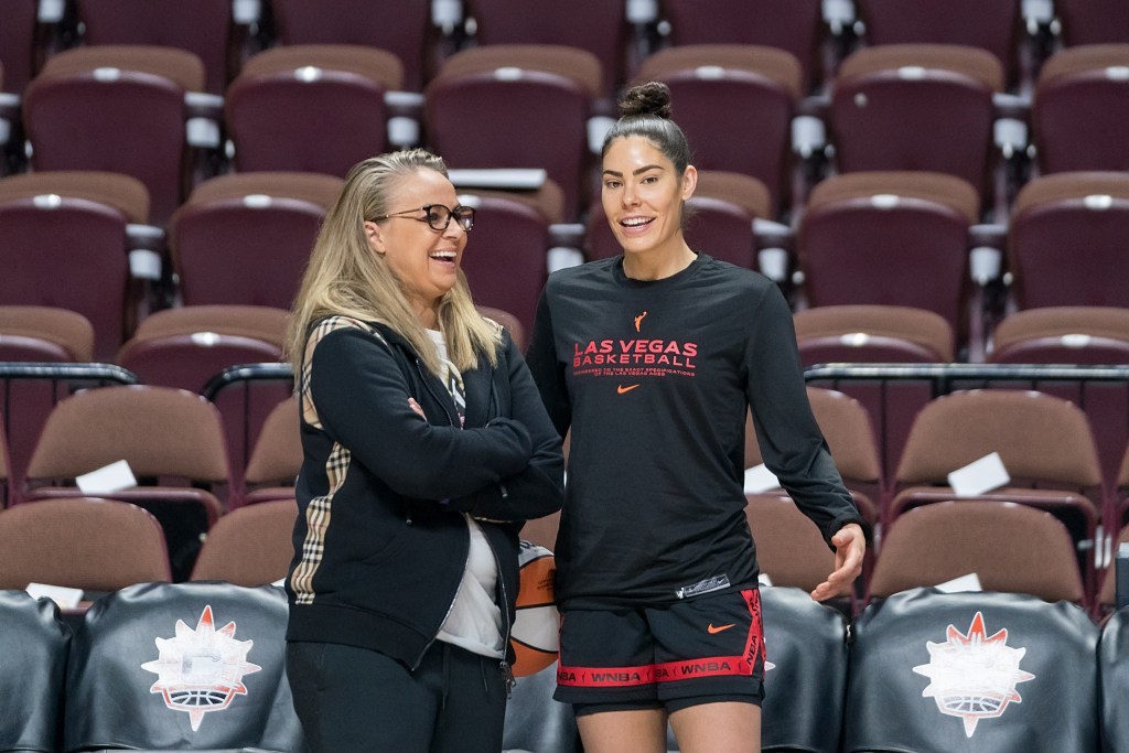 Las Vegas Aces head coach Becky Hammon has her arms folded across her chest as she laughs with guard Kelsey Plum.