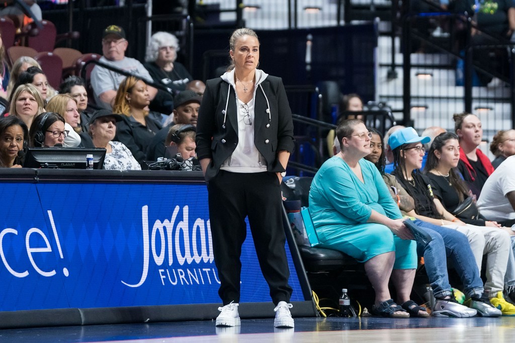 Las Vegas Aces head coach Becky Hammon stands in front of the scorer's table with her hands in her pockets.