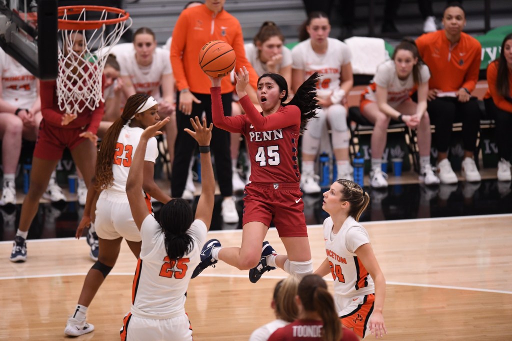Penn's Kayla Padilla turns her body in mid-air to shoot. Her shoulders are square and her legs are bent underneath her.