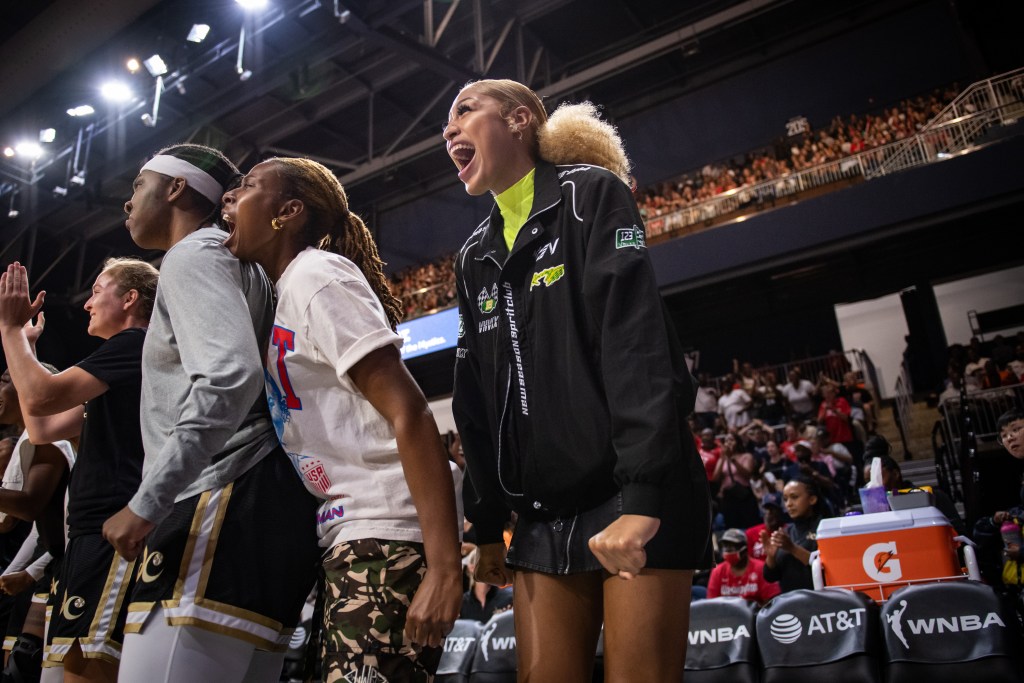 Wearing street clothes, injured Washington Mystics center/forward Shakira Austin yells in celebration on the bench.