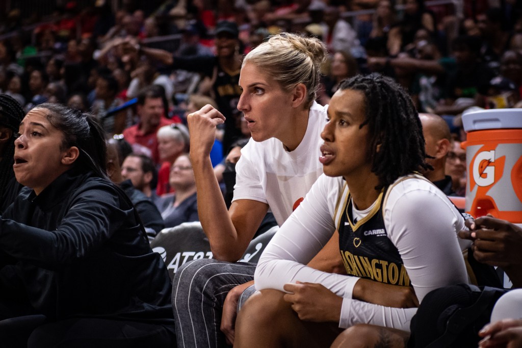 Washington Mystics forwards Elena Delle Donne and Cyesha Goree sit on the bench during a game. Delle Donne is in street clothes, while Goree is in her uniform.