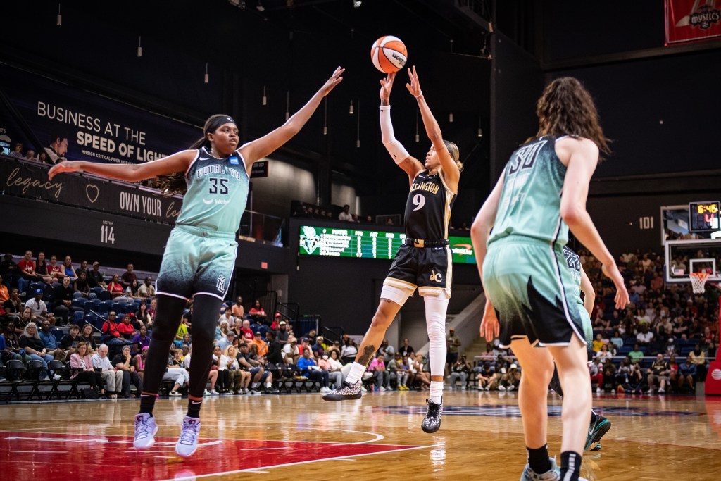 Washington Mystics point guard Natasha Cloud shoots a mid-range jump shot as New York Liberty forward Jonquel Jones contests with her left hand.