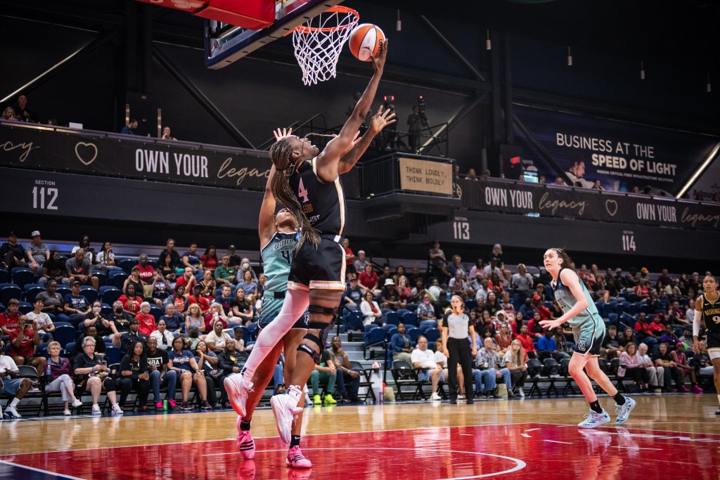 Washington Mystics center Queen Egbo attempts a reverse layup with her right hand as a defender pressures her.