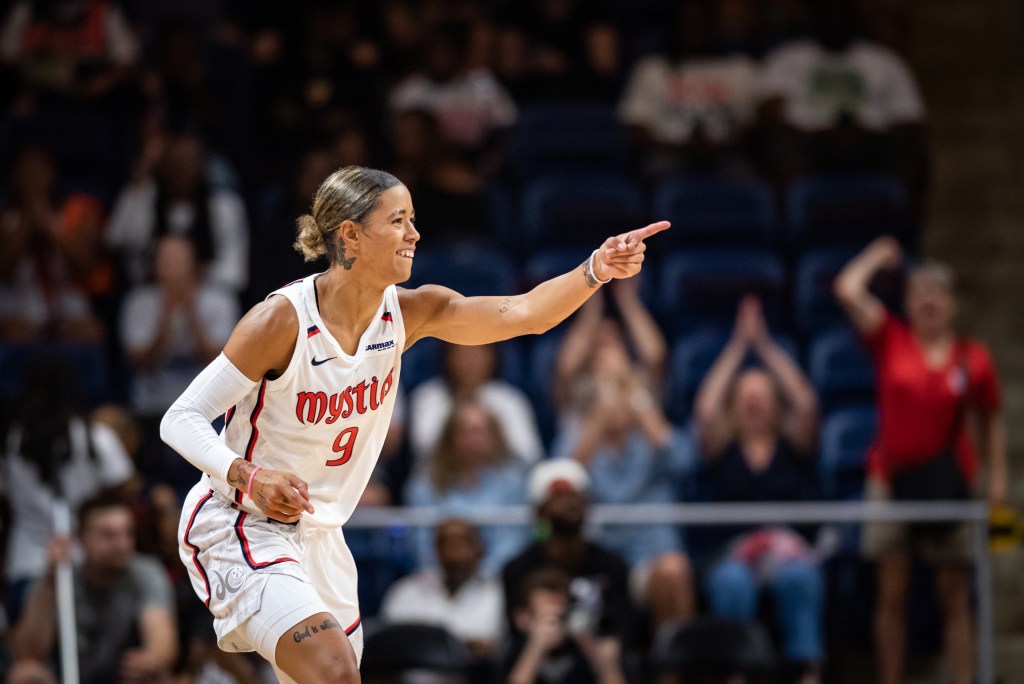 Washington Mystics point guard Natasha Cloud smiles and points her left hand straight out in front of her.