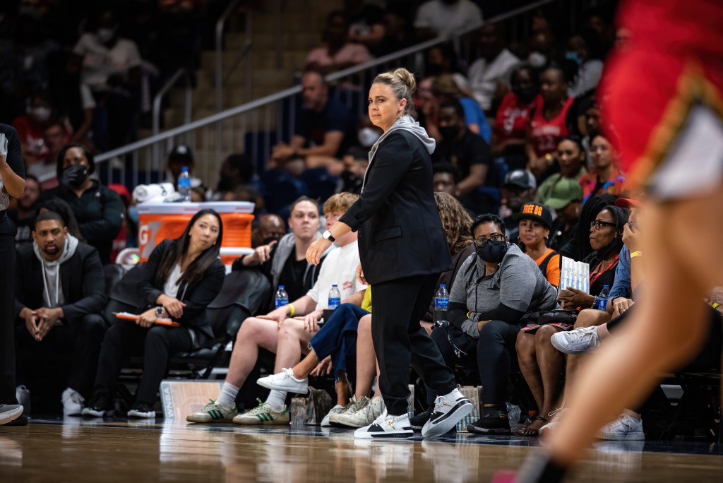 Las Vegas Aces head coach Becky Hammon walks down the sideline, turning her body toward the action on the court.