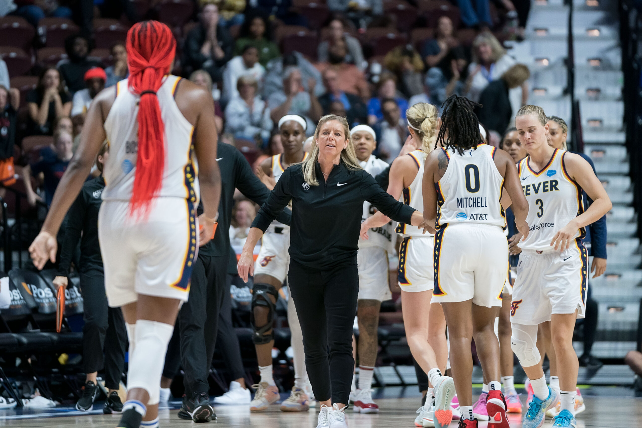 Indiana Fever head coach Christie Sides walks onto the court to high-five her players after the final buzzer.