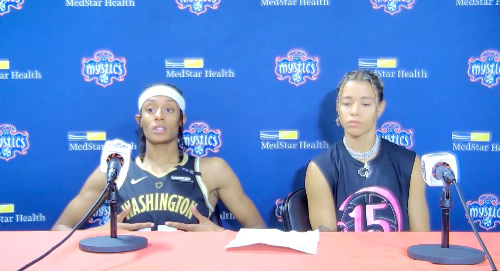 Washington Mystics guard Brittney Sykes sits at the podium and pats her No. 15 jersey as she talks to reporters about the late Nikki McCray-Penson, who wore the same number.