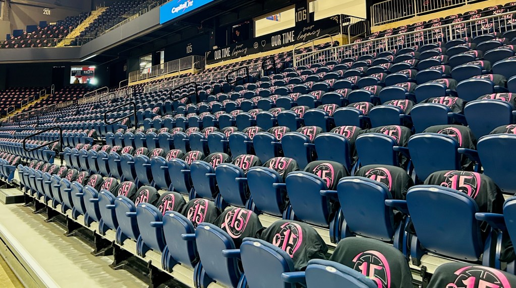 Rows of empty blue seats at the Entertainment and Sports Arena. Each seat has a black and pink shirt on it in honor of the late Nikki McCray-Penson.