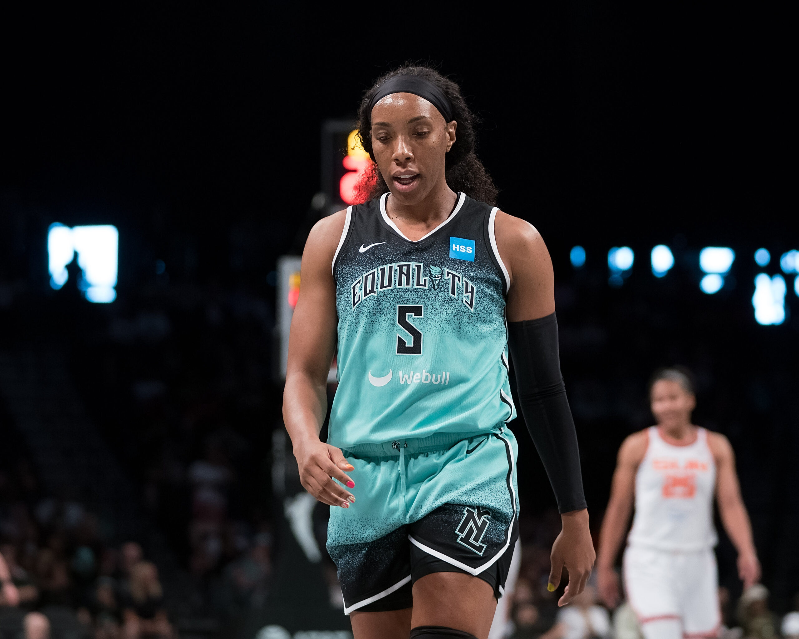 Wearing a seafoam green jersey, New York Liberty forward Kayla Thornton walks down the court toward the camera.