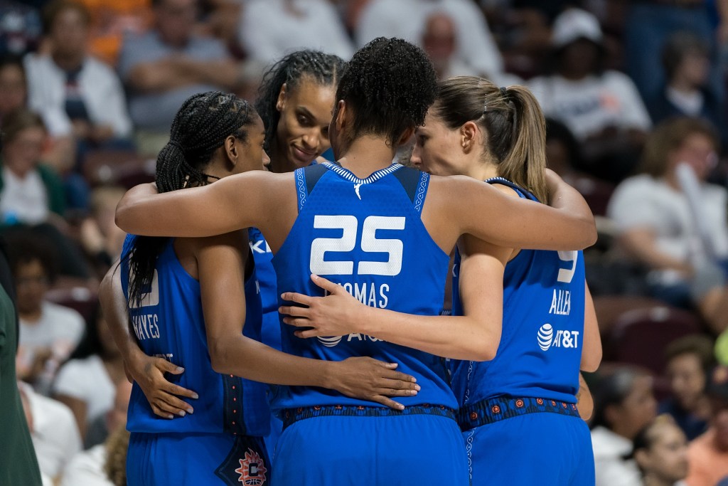 Connecticut Sun players wrap their arms around each other in a tight huddle.