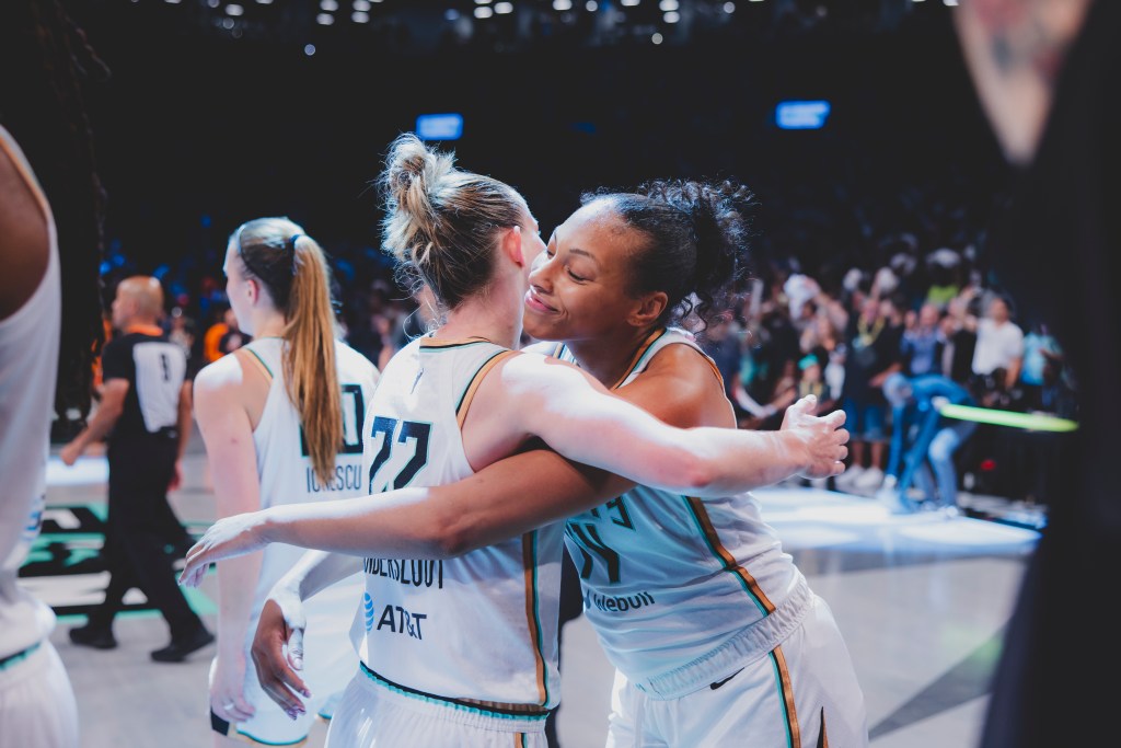 Betnijah Laney smiles and hugs her teammate Courtney Vandersloot.