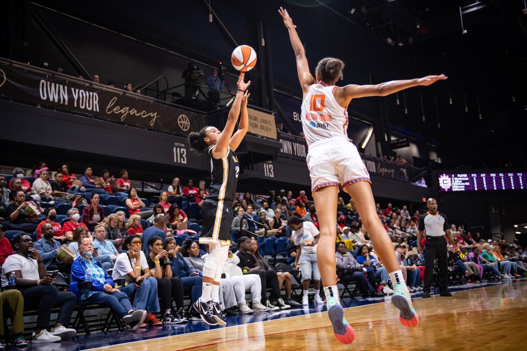 Washington Mystics guard Kristi Toliver shoots a deep jump shot as Connecticut Sun center Olivia Nelson-Ododa leaps toward her and contests with her left hand.