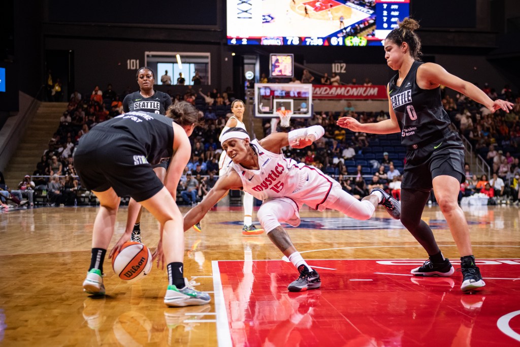 Washington Mystics guard Brittney Sykes extends her right arm and reaches for a ball as Seattle Storm guard Jade Melbourne also looks to gather it.
