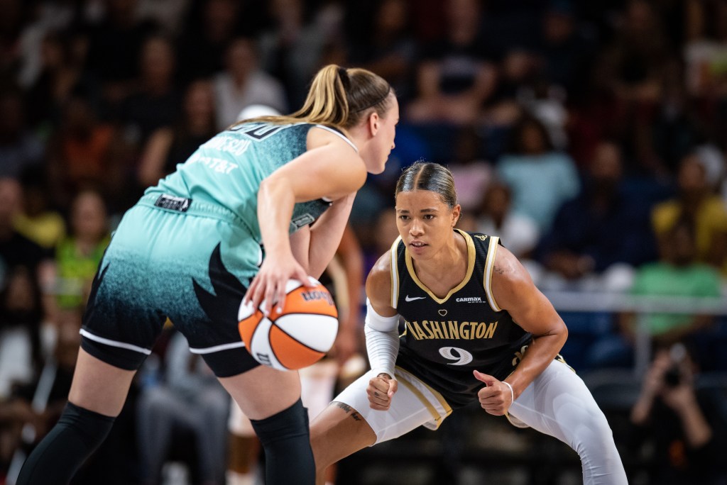 Washington Mystics guard Natasha Cloud sits low in a wide defensive stance with her eyes laser focused on the ball.
