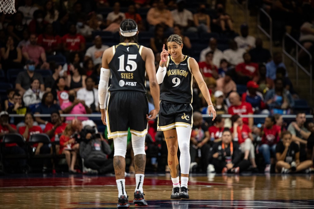 Washington Mystics guards Natasha Cloud and Brittney Sykes walk toward each other. Cloud smiles and points at Sykes.