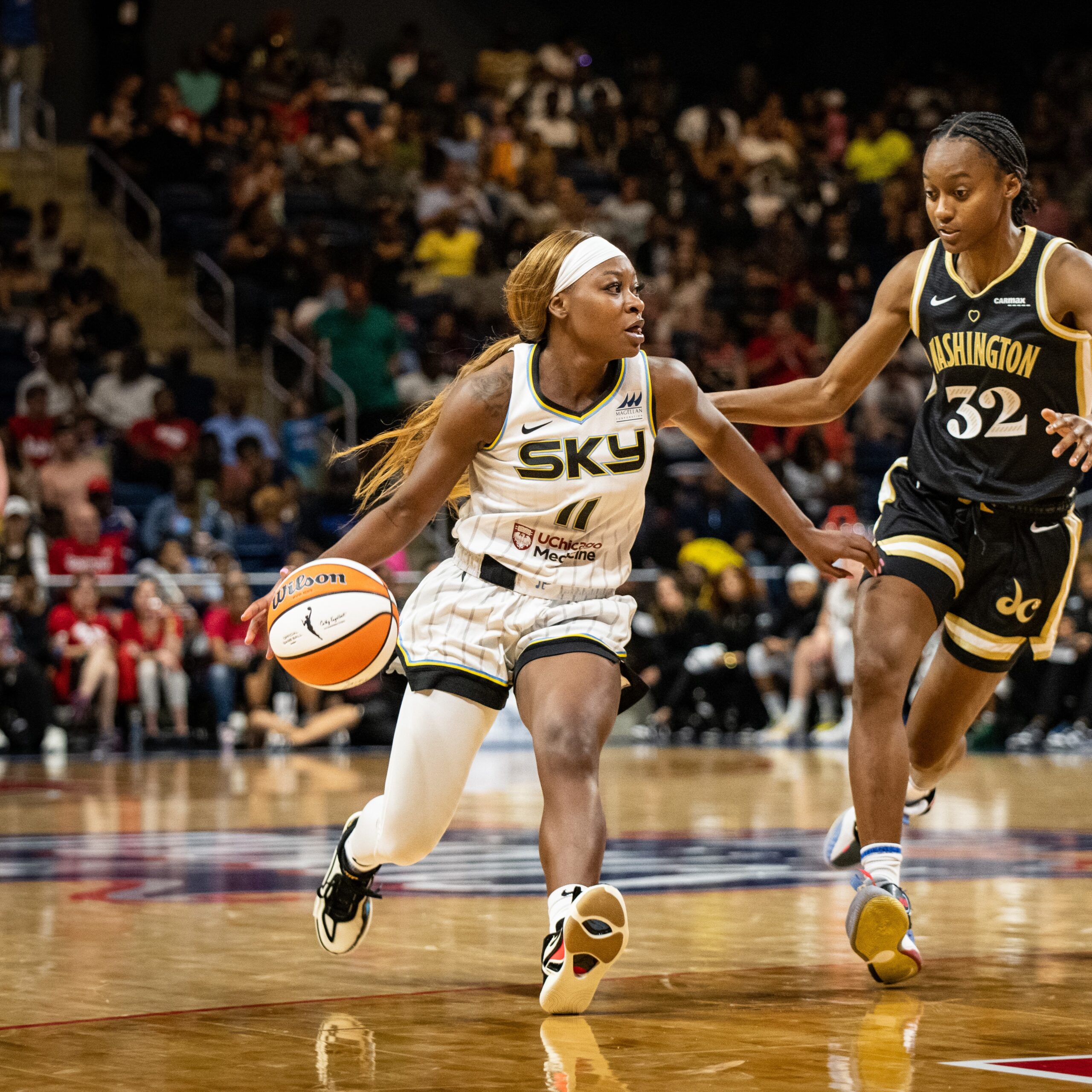 Chicago Sky guard Dana Evans dribbles downhill in a WNBA game while looking across the court past her defender, Washington Mystics wing Shatori Walker-Kimbrough, side-stepping alongside