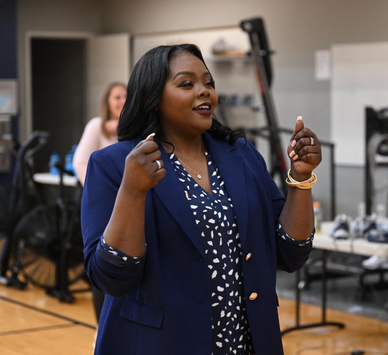 Georgetown women's basketball head coach Tasha Butts is pictured in a navy blazer over a spotted blouse. She is speaking during her introduction to the media as the program's new head coach.