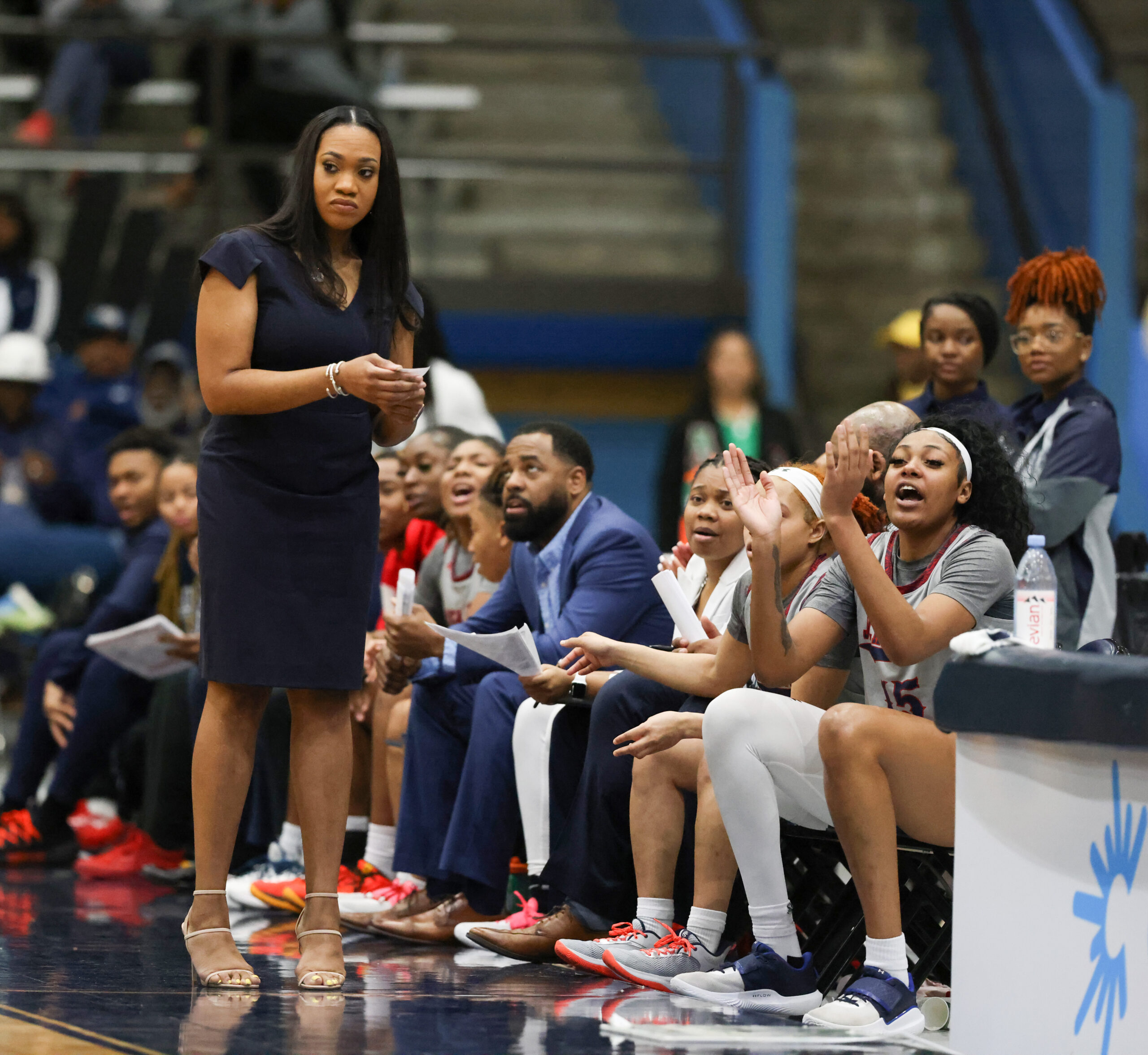 Jackson State head coach Tomekia Reed stands on the sidelines during a game. She holds a piece of paper and looks less than pleased as she watches her team.