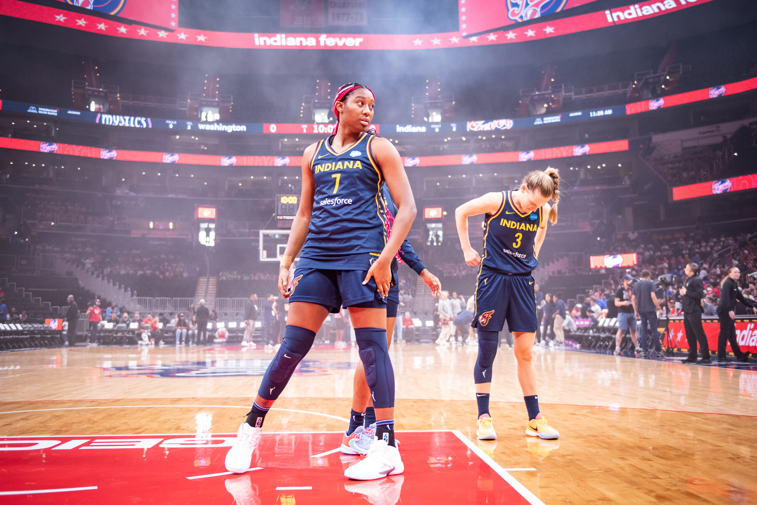 Indiana center Aliyah Boston, the unanimous Rookie of the Year, stands on the court in front of two Fever teammates during pregame player introductions while surrounded by smoke.