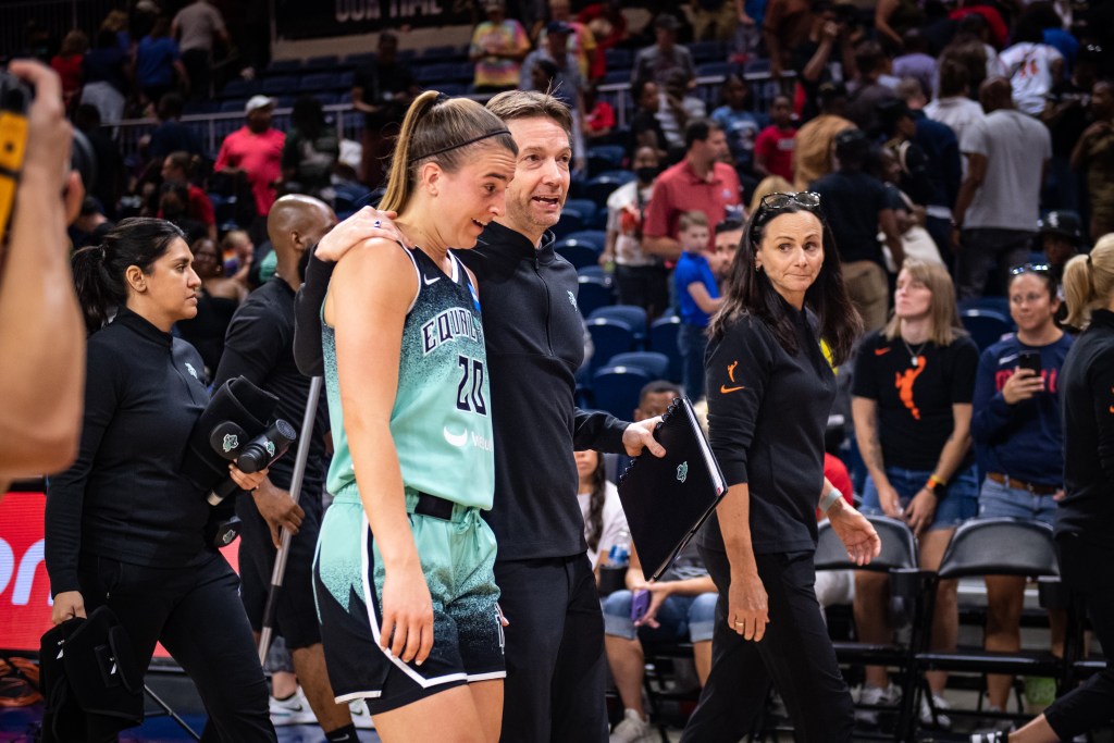 Sabrina Ionescu and Olaf Lange chat while Sandy Brondello listens.