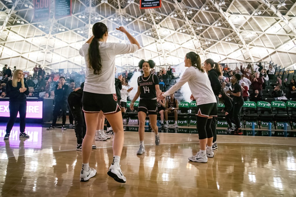 Harvard guard Harmoni Turner walks onto the court and high-fives her teammates as she is introduced as a starter.