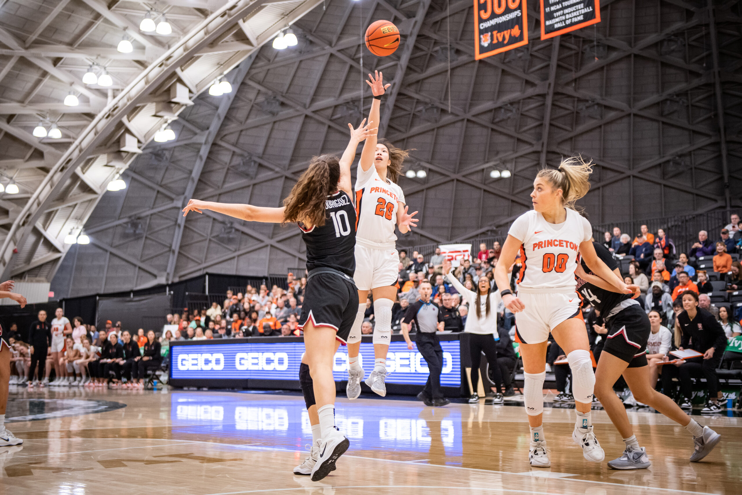 Princeton guard Kaitlyn Chen shoots a right-handed midrange floater as Harvard forward Elena Rodriguez tries to contest with her right hand. Princeton forward Ellie Mitchell runs toward the basket while looking back at Chen.