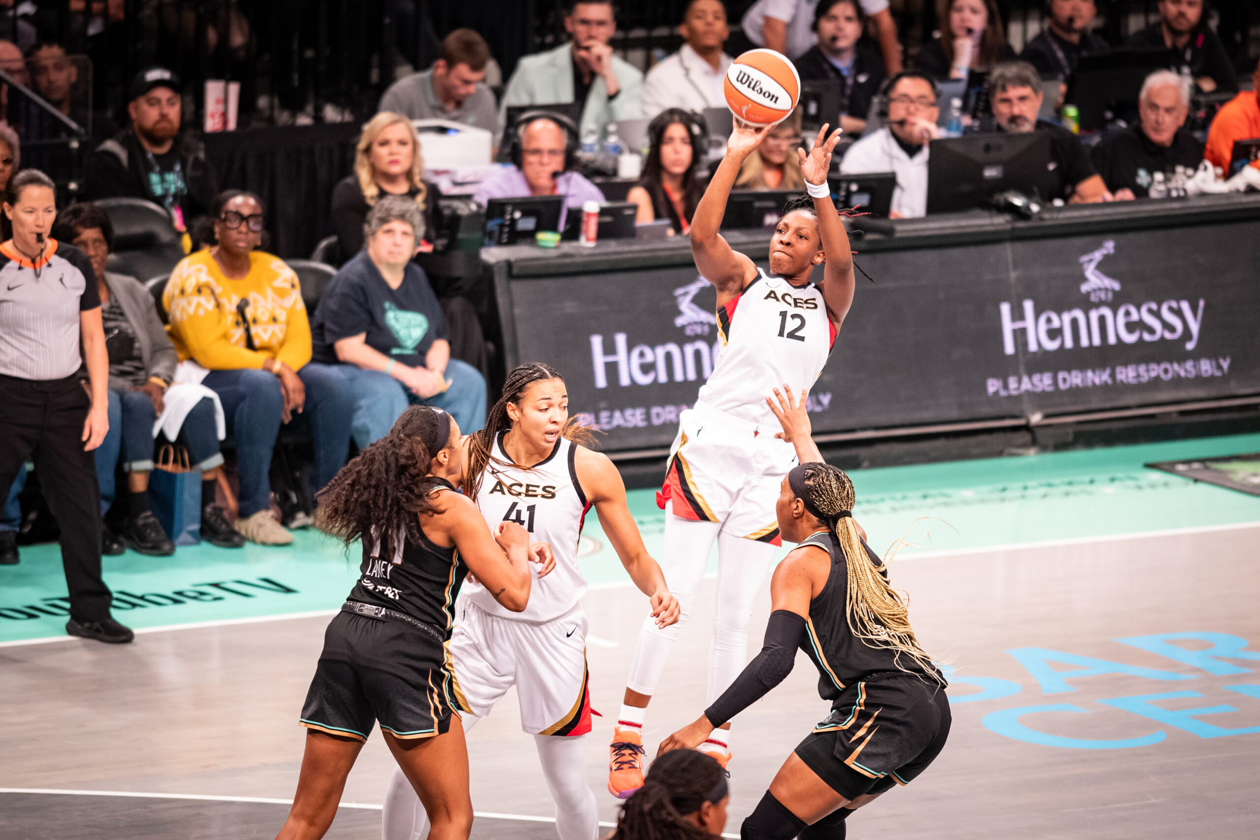 Las Vegas Aces guard Chelsea Gray shoots a fadeaway jump shot over two New York Liberty defenders while center Kiah Stokes sets a screen.