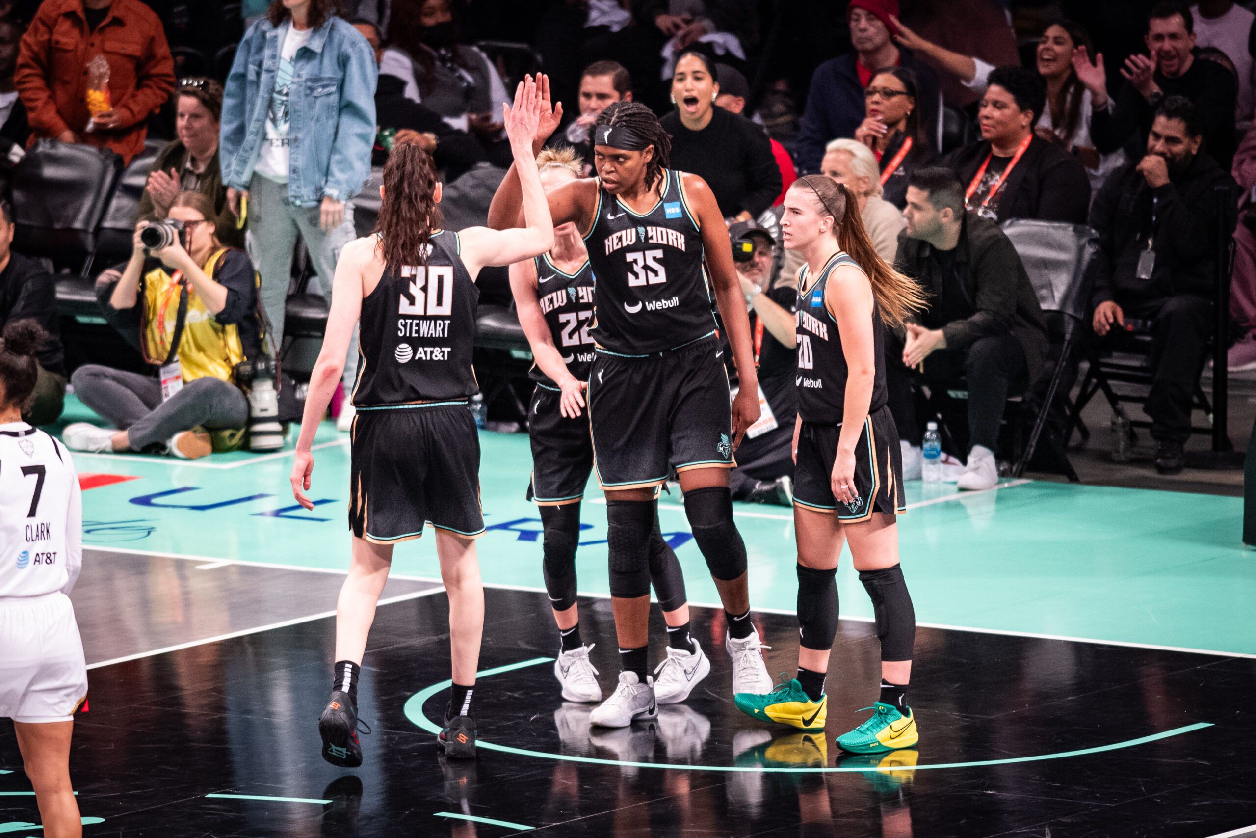 New York Liberty forward Jonquel Jones stands in the middle of her teammates as they congratulate her.