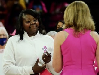 Tasha Butts is pictured wearing a white Georgia Tech sweat suit top while receiving acknowledgment from Debbie Antonelli, whose back is in the foreground of the photo wearing a pink top.