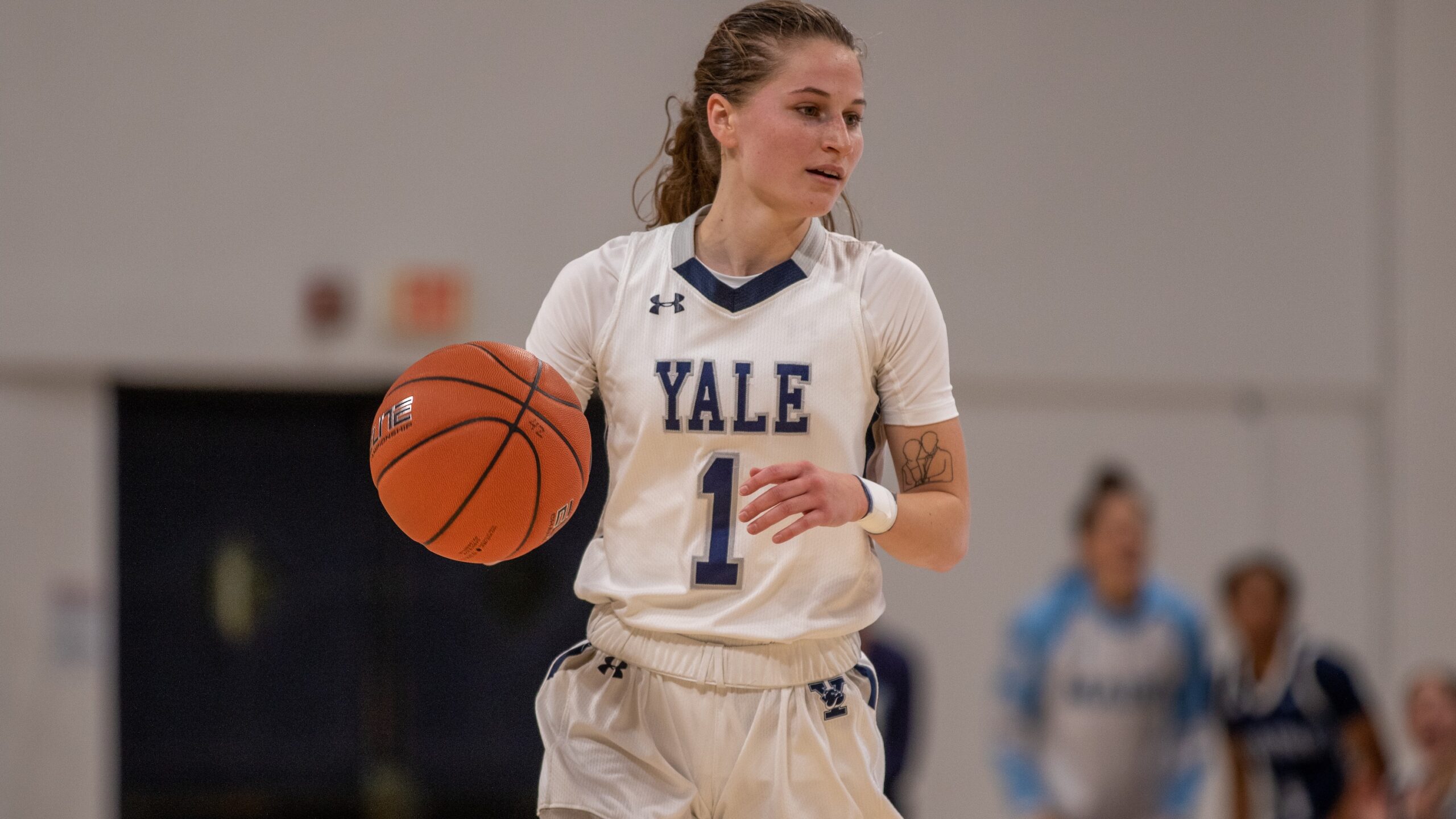 Yale point guard Jenna Clark dribbles the ball with her right hand and gazes slightly to her left.