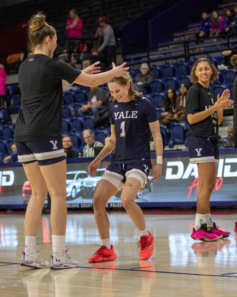 During starting lineup introductions, Yale point guard Jenna Clark smiles and lowers her head as a teammate pantomimes putting a crown on her.
